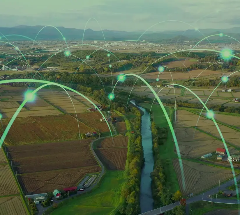 Luftaufnahme von Ackerland mit überlagerten digitalen Netzwerkleitungen und leuchtenden Knoten, die intelligente Agrartechnologie und vernetzte ländliche Infrastruktur symbolisieren.